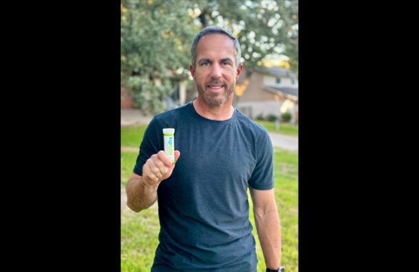 Man holding a product in front of a blurred outdoor background