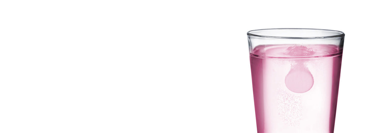 Clear glass filled with pink liquid on a white background