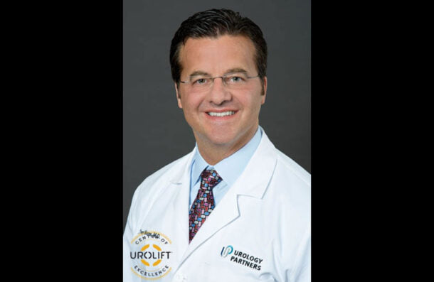 Man wearing a white lab coat with logos on a gray background